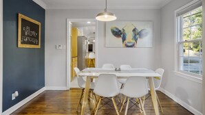 En matplats med ett vitt bord och stolar, en taklampa, en tavla som föreställer en ko och en skylt med texten ”Välkommen” på väggen.