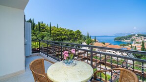 A balcony with a round table, wicker chairs, and a vase with flowers. - Amazing home in Cavtat (Cavtat)