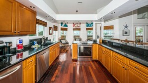 A spacious kitchen with wooden cabinets, a black countertop, and a stainless steel oven.