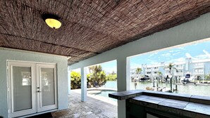 A covered outdoor area with a pool, a refrigerator, and a view of a marina with boats.