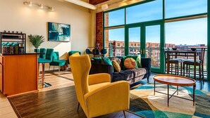 Amplia sala de estar con un ventanal, un sofá, un sillón amarillo y una estación para café.