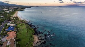 Vue aérienne d’une zone côtière comprenant une plage, un littoral rocheux et des immeubles résidentiels.