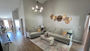 Amplia sala de estar con un sofá grande, una mesa de centro y una araña.