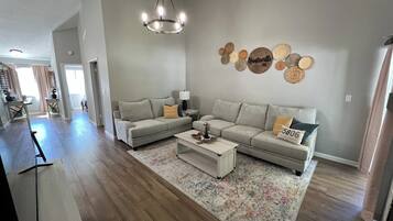 A spacious living room with a large sofa set, a coffee table, and a chandelier.