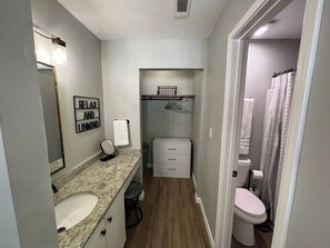 Un baño pequeño con lavamanos, espejo, toallero y un armario.