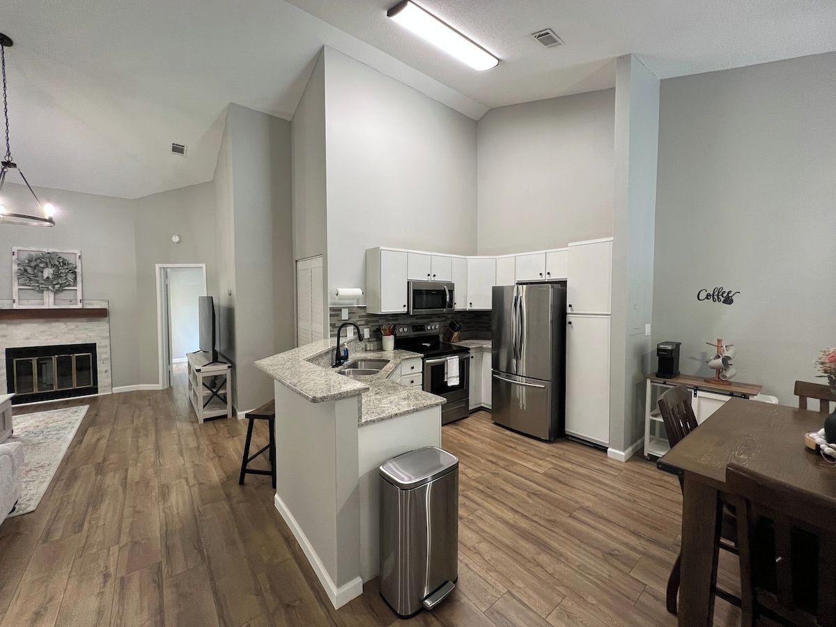 A modern kitchen with a central island, stainless steel appliances, and a dining area with a wooden table.