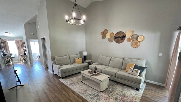 Een moderne woonkamer met een zithoek, een salontafel en een kroonluchter.