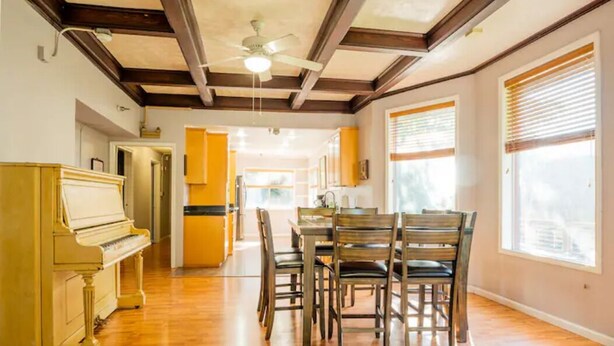 A spacious dining area with a wooden table and chairs, a piano, and a ceiling fan. - Top of Tacoma Flat Unit 1 (Tacoma)