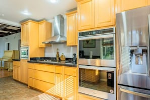 A modern kitchen with stainless steel appliances, wooden cabinets, and a built-in oven.