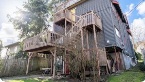 A two-story house with a wooden deck and a fenced backyard. - Top of Tacoma Flat Unit 1 (Tacoma)