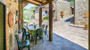 An outdoor patio with stone flooring, wooden beams, and a table with chairs. - Beautiful apartment for 6 people with WIFI, pool, TV, patio and panoramic view (Reggello)