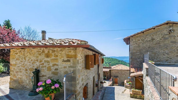 A narrow stone pathway leading to traditional stone buildings with terracotta roofs, surrounded by greenery and a clear sky. - Beautiful apartment for 6 people with WIFI, pool, TV, patio and panoramic view (Reggello)
