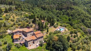 A stone villa with a swimming pool surrounded by lush greenery and mountains in the background. - Beautiful apartment for 6 people with WIFI, pool, TV, patio and panoramic view (Reggello)