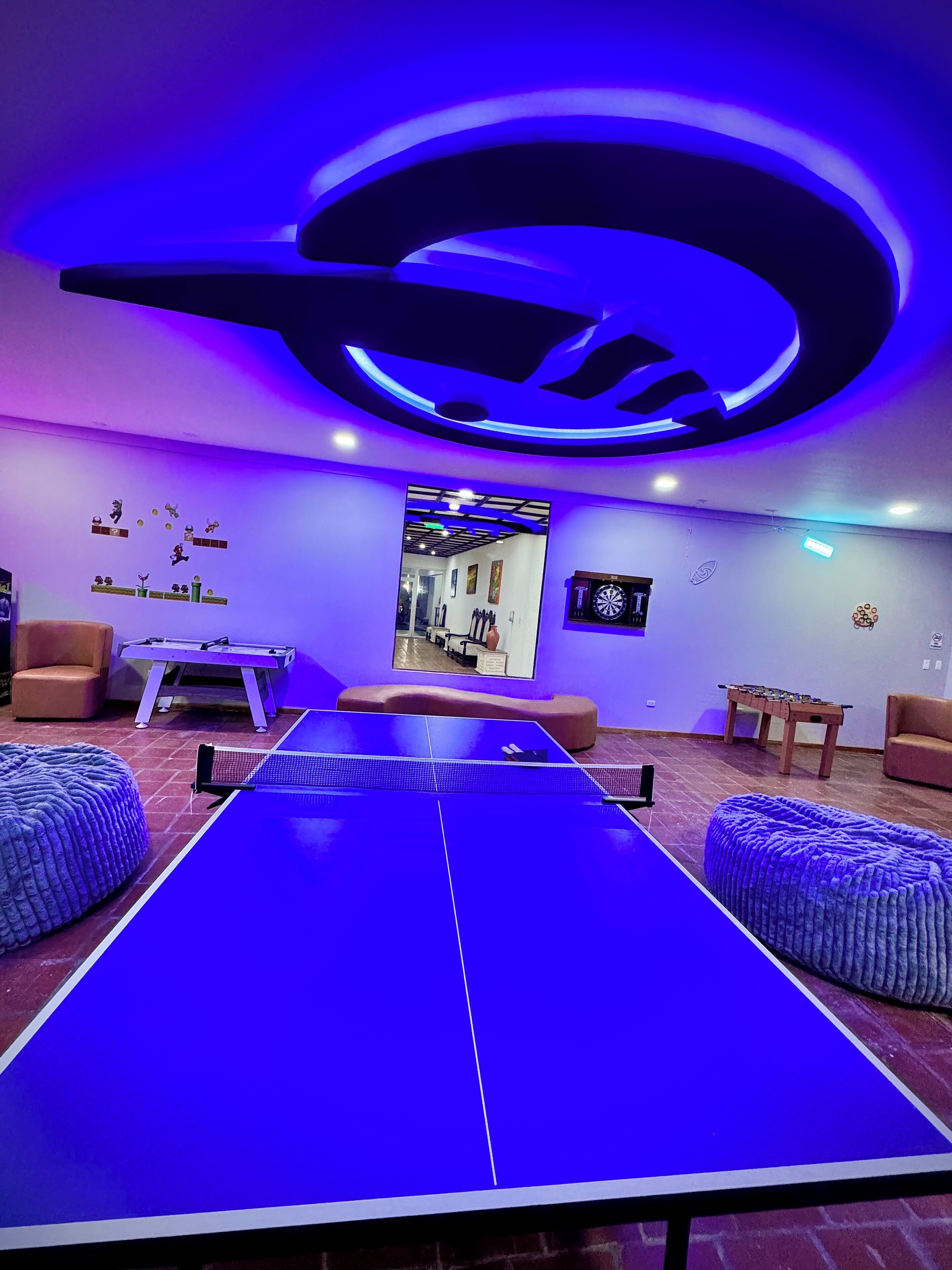 Une pièce équipée d’une table de ping-pong, de canapés et d’un jeu de fléchettes.
