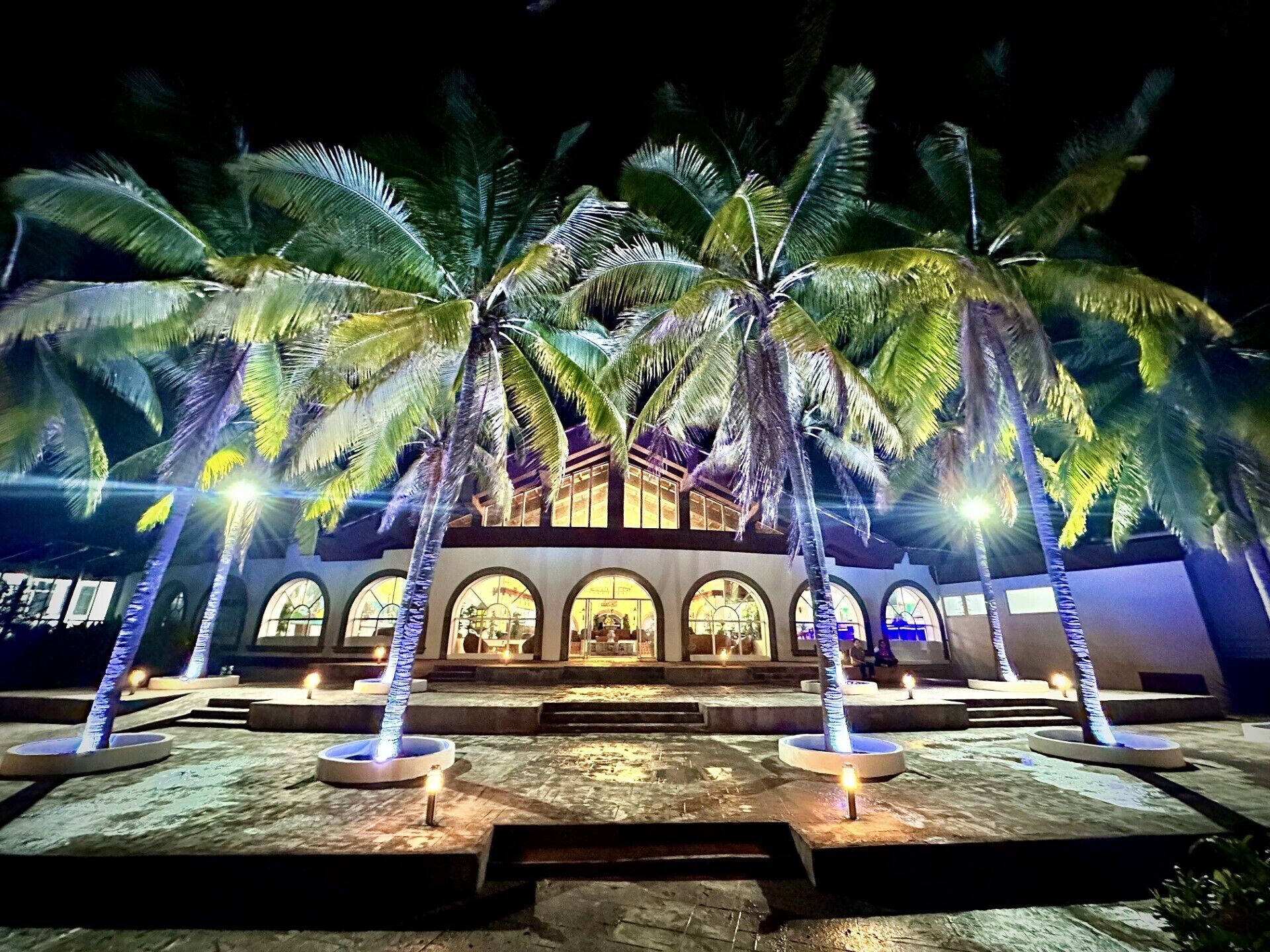 A building with arched windows and a courtyard with palm trees.