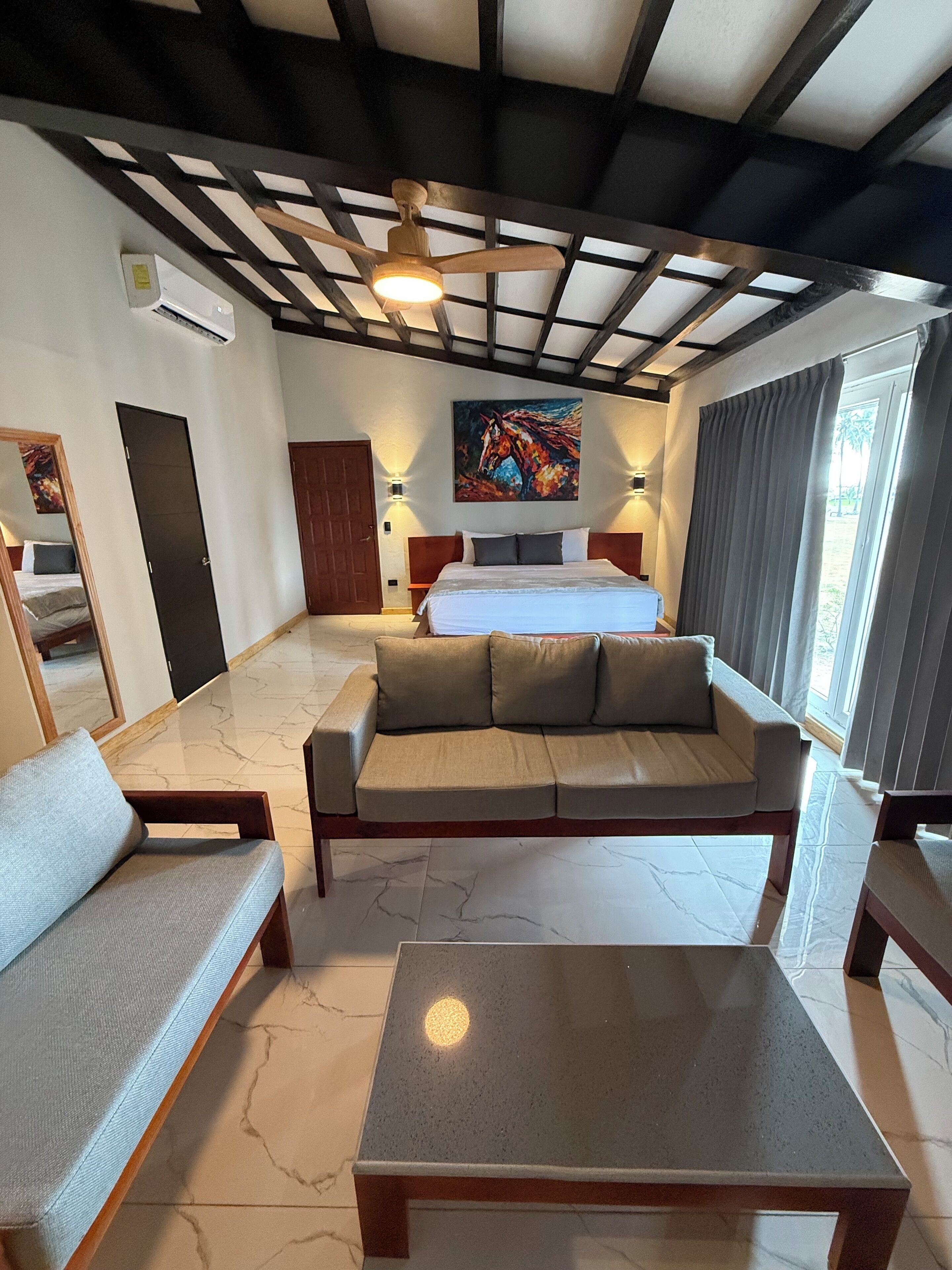 Een hotelkamer met een bed, een bank, een salontafel en een plafondventilator.