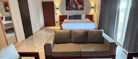 A hotel room with a bed, a sofa, a coffee table, and a ceiling fan.