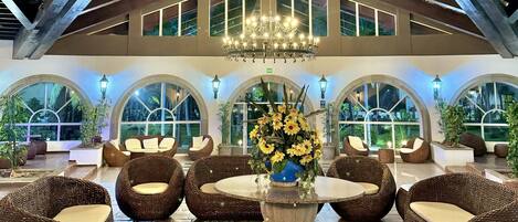 A spacious lobby with high ceilings, a large chandelier, and comfortable seating areas.