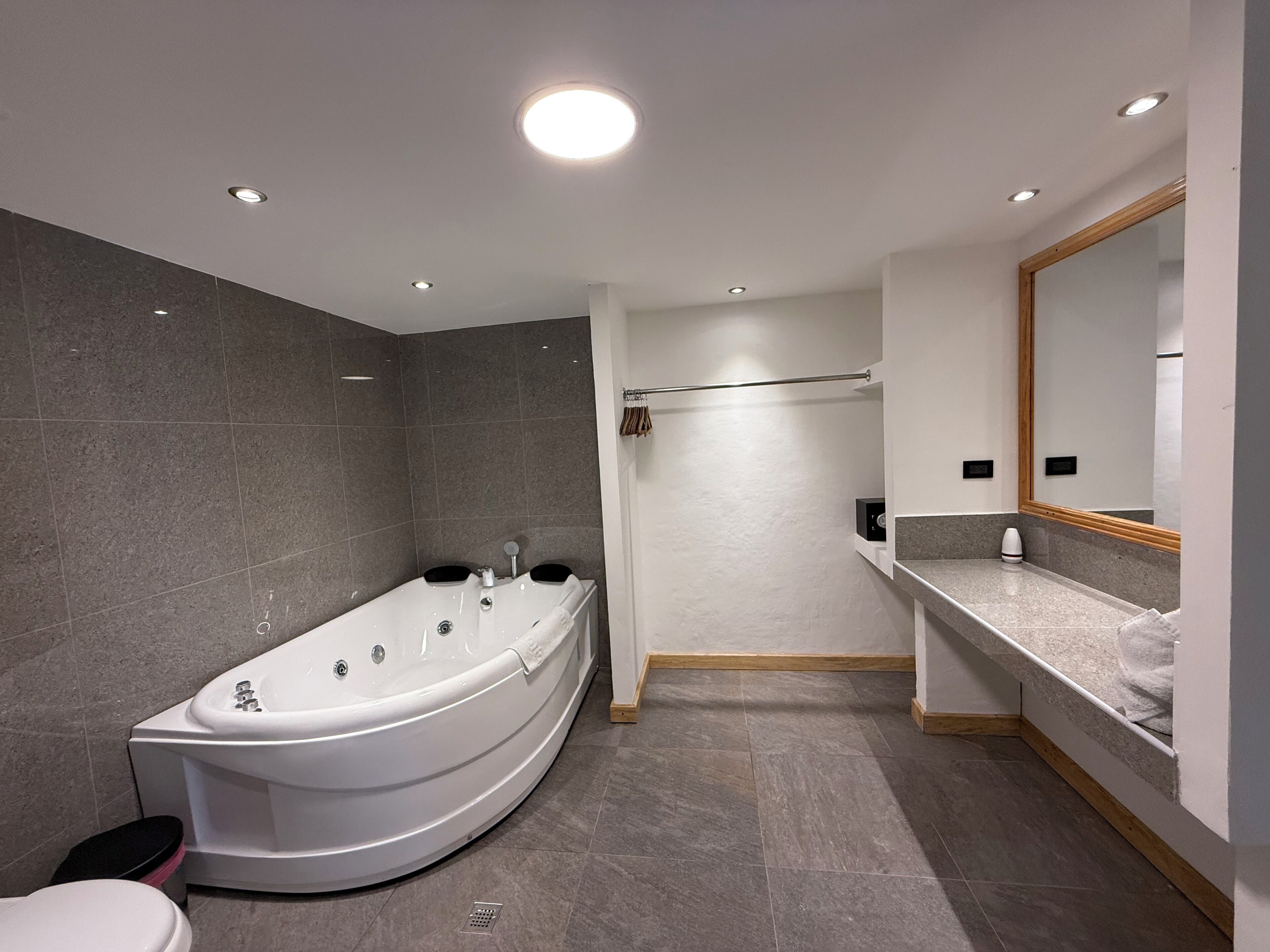 Un bagno moderno con una vasca da bagno indipendente, un water, zona doccia e un mobile lavabo con specchio.