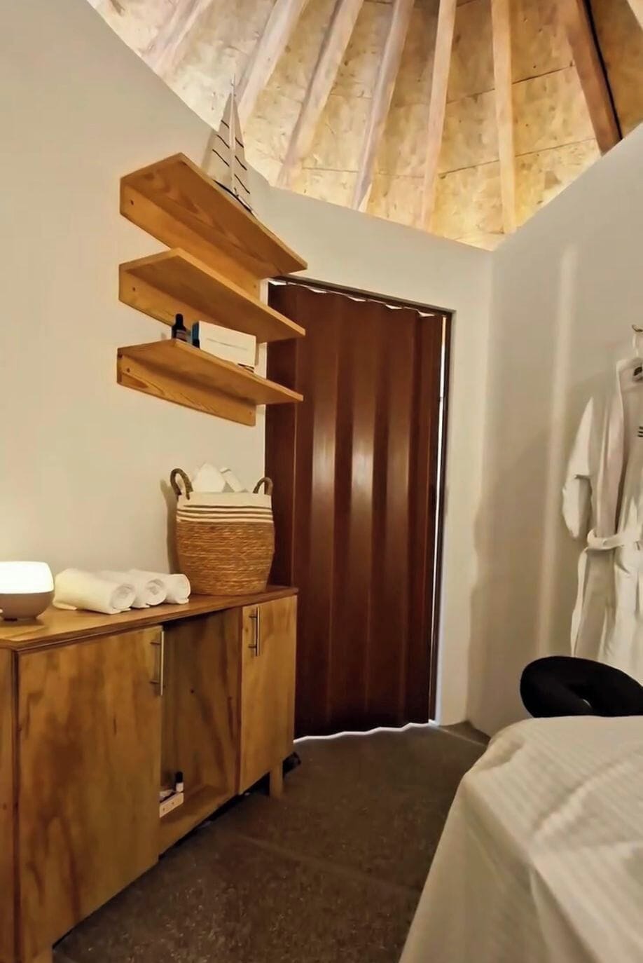 A room with a wooden cabinet, a basket, and a towel rack.