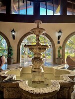 A stone fountain with water spouting from its center, surrounded by stone benches and potted plants.