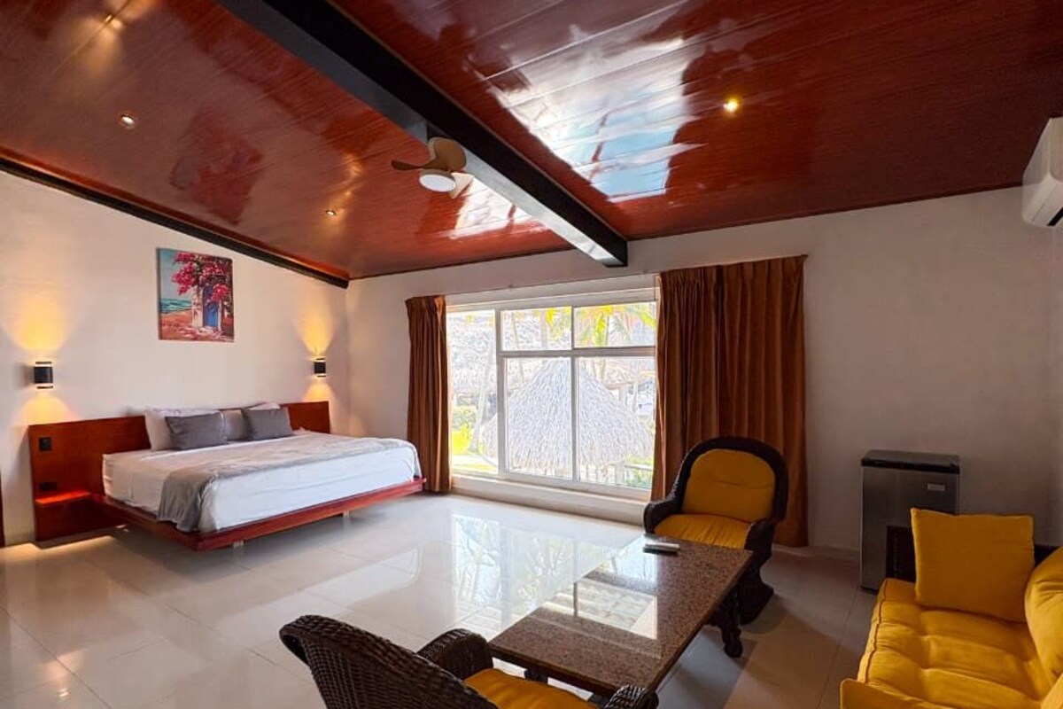A spacious room with a bed, a dining table, and a sofa.