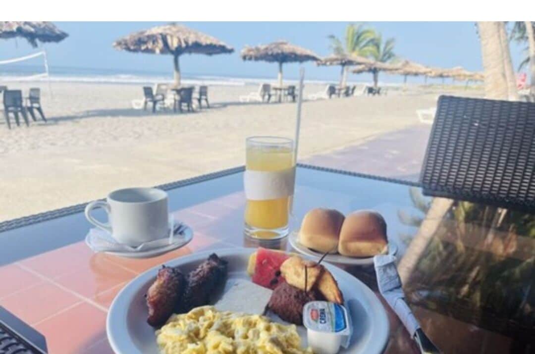 Una mesa de desayuno con un plato de comida, un vaso de jugo de naranja y una taza de café.