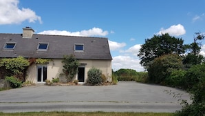 Une maison à deux étages avec une grande allée et un jardin à l’avant.