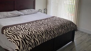 Un dormitorio con cama, ventilador de techo, ventana con persianas y vista al exterior.