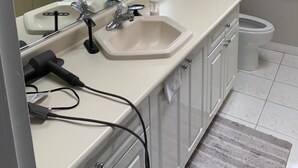 Un baño con lavamanos, espejo e inodoro.