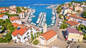 A marina with boats docked, surrounded by residential buildings with red roofs. - Holiday apartment in the center of Njivice (Njivice)
