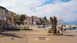 A marina with boats, a central tree sculpture, and outdoor seating areas. - Holiday apartment in the center of Njivice (Njivice)