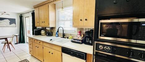 Una cocina con armarios de madera, lavavajillas, microondas y cafetera.