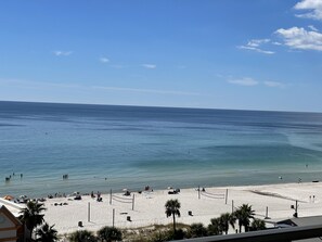 A beach with clear blue water, people swimming, and umbrellas.