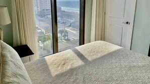 Ein Schlafzimmer mit großem Fenster, einem Bett und einem Nachttisch.