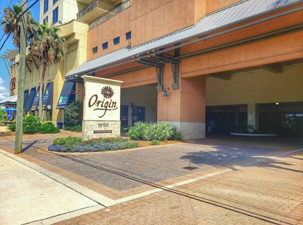 A hotel entrance with a sign reading 'Origin' and the address '15100 Registration.'