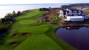 Ein Golfplatz mit Bunkern, einem Clubhaus und einem Wasserhindernis.