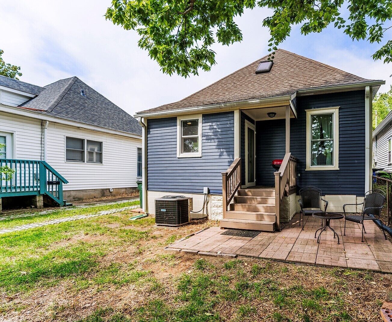 A residential house with a front porch, a staircase, and a small outdoor seating area.