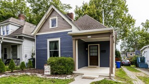 Une maison à deux étages avec un porche à l’avant, une petite fenêtre et une boîte aux lettres.