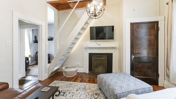 Un salon avec une cheminée, un escalier et un téléviseur fixé au-dessus de la cheminée.