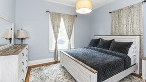 Une chambre à coucher avec un lit, une commode et une lampe suspendue.