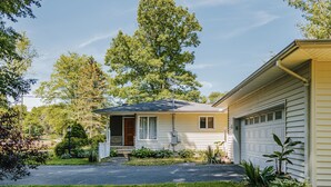 Een gelijkvloers huis met een veranda, een garage en een verzorgd gazon.