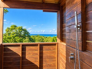 Una cabaña de madera con ducha integrada y vista al océano.