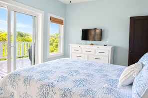 A bedroom with a bed, a television, a dresser, and a door.