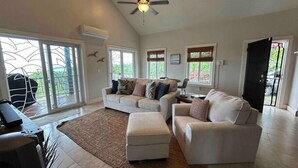 A spacious living room with a high ceiling, a ceiling fan, and large windows. - Havana Palms, 2 Bedroom Paradise (Milton Bight)