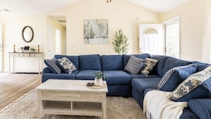 A living room with a blue sectional sofa, a wooden coffee table, and a white console table with decorative items. - Centally located w/ coffee bar, theatre/gameroom (Orangeburg)