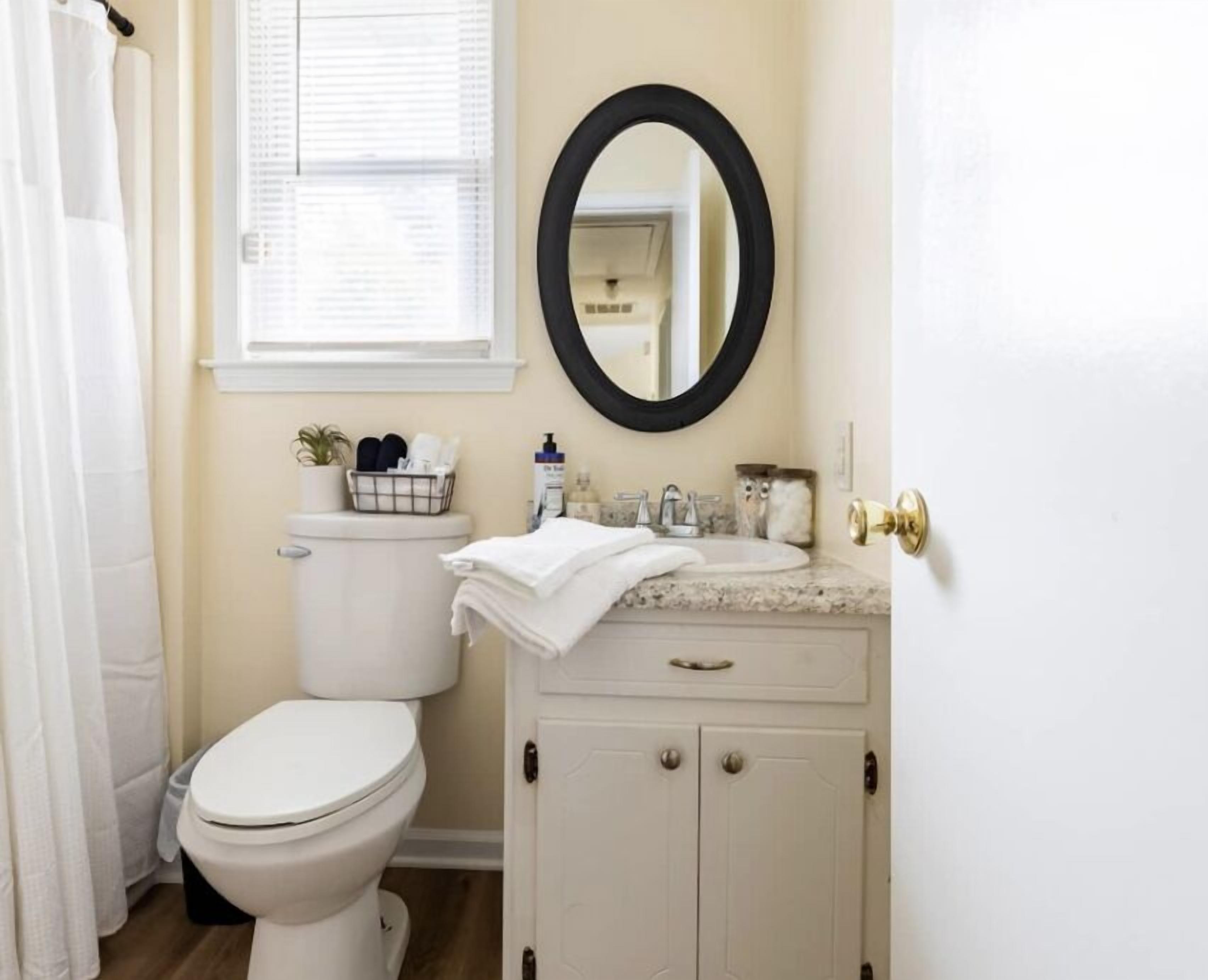 A bathroom with a toilet, sink, and mirror.