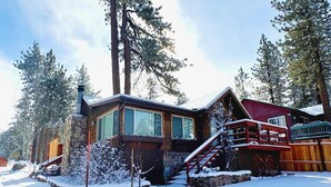 Une cabane avec des fondations en pierre, de grandes fenêtres et une terrasse en bois.