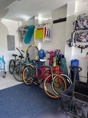 A room with bicycles, a stroller, and a baby stroller.