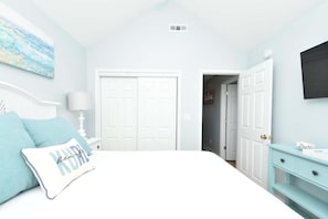 A bedroom with a bed, a nightstand, a dresser, and a wall-mounted TV. - 5 Decks, Pool, Walk to Pier & Boardwalk (Kure Beach)